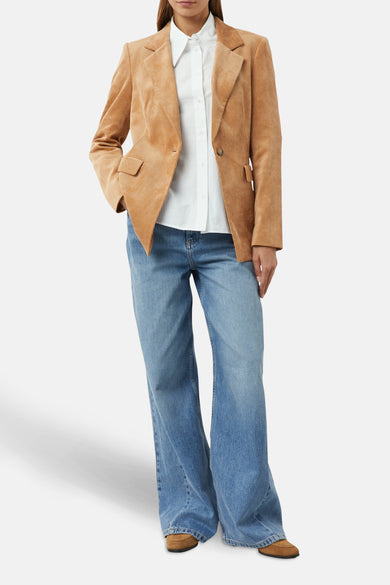Cognac corduroy blazer van COMMA, gedragen over een wit overhemd en een uitlopende blauwe jeans.