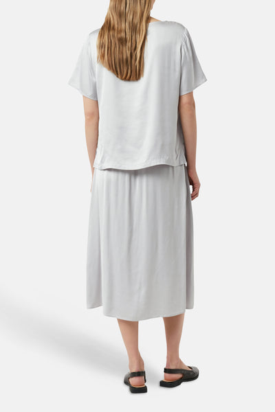 Blouse à manches courtes grise de COMMA, avec une jupe de couleur assortie et des chaussures noires.