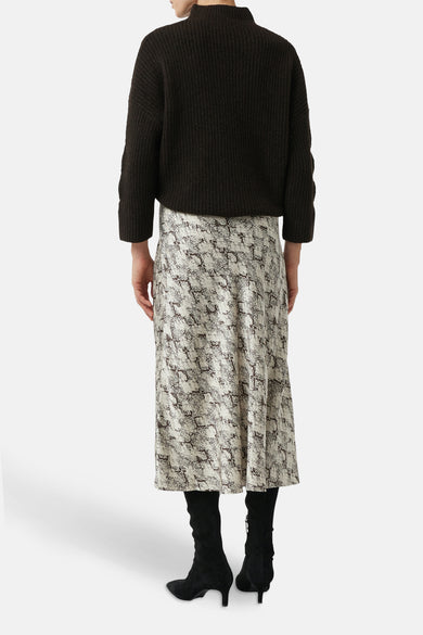 3/4 meerkleurige rok van COMMA, met slangenprint en gedragen met zwarte laarzen.