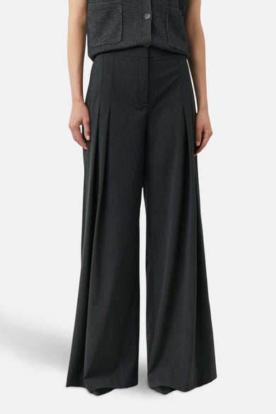 Grijze pantalon van COMMA, met plooien en wijde pijpen, gedragen met een grijze cardigan.