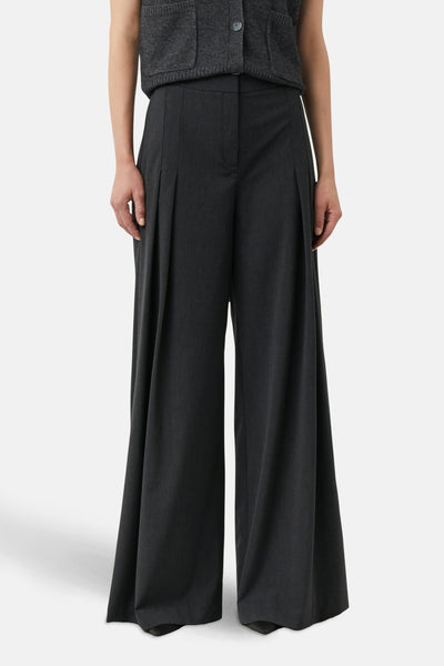 Grijze pantalon van COMMA, met plooien en wijde pijpen, gedragen met een grijze cardigan.
