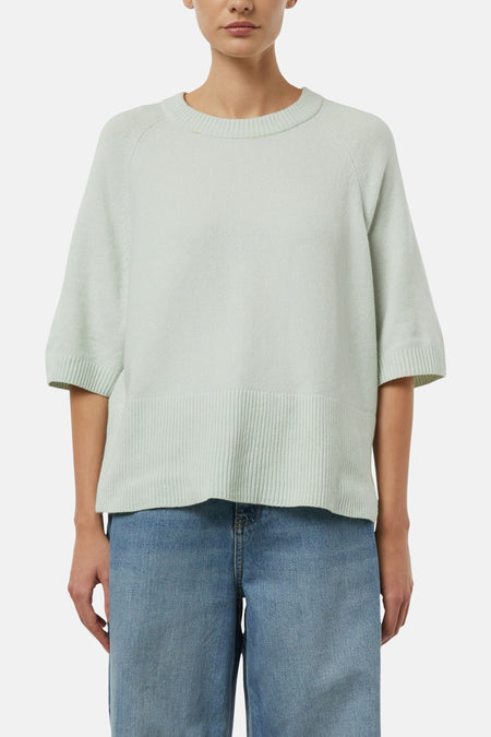 Pull col rond vert de COMMA, avec manches courtes et ourlet côtelé, porté avec un jean bleu.
