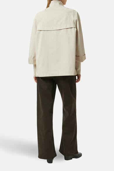 Veste courte beige de COMMA, avec une coupe ample et des manches retroussées, portée avec un pantalon marron foncé.
