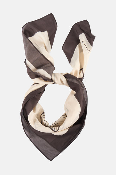 Multicolored silk foulard by DOMA, featuring brown and cream stripes with subtle geometric patterns, tied in a knot against white background