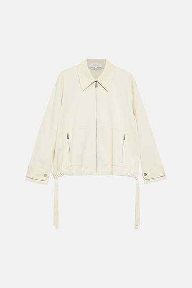 Korte beige jas van COMMA, met zilveren ritssluiting en strikdetails.