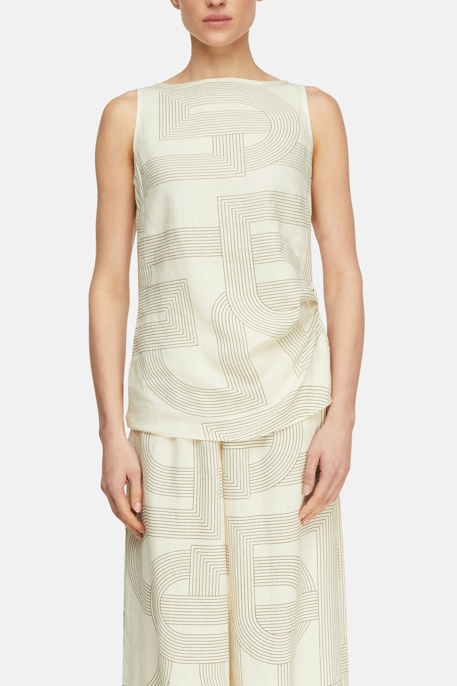 Blouse sans manches beige de COMMA, avec un motif géométrique de lignes marron et un col bateau, portée avec un pantalon assorti.