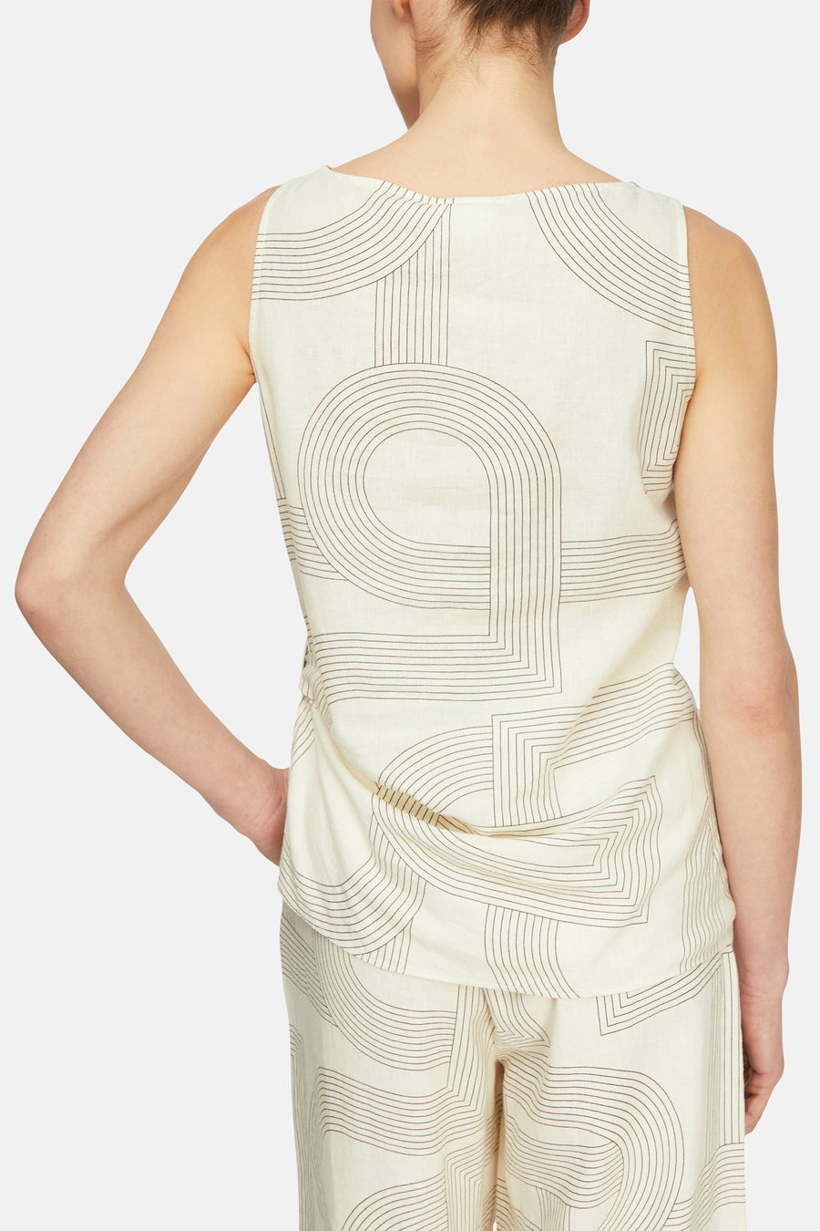 Blouse sans manches beige de COMMA à motif géométrique de lignes marron, portée de dos avec un pantalon assorti.