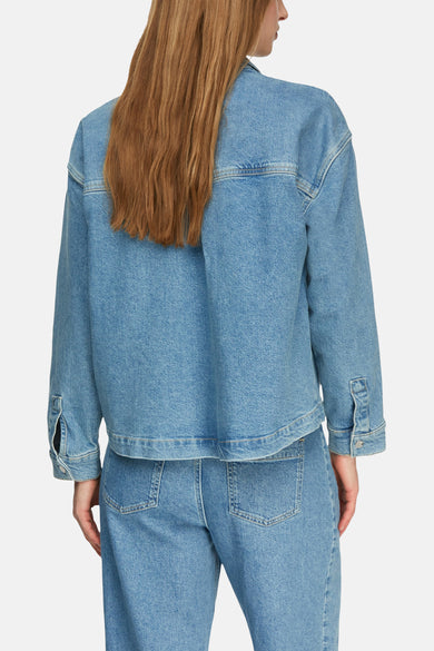 Veste courte en denim bleu moyen de COMMA, présentée de dos, avec des coutures apparentes et des poignets boutonnés.
