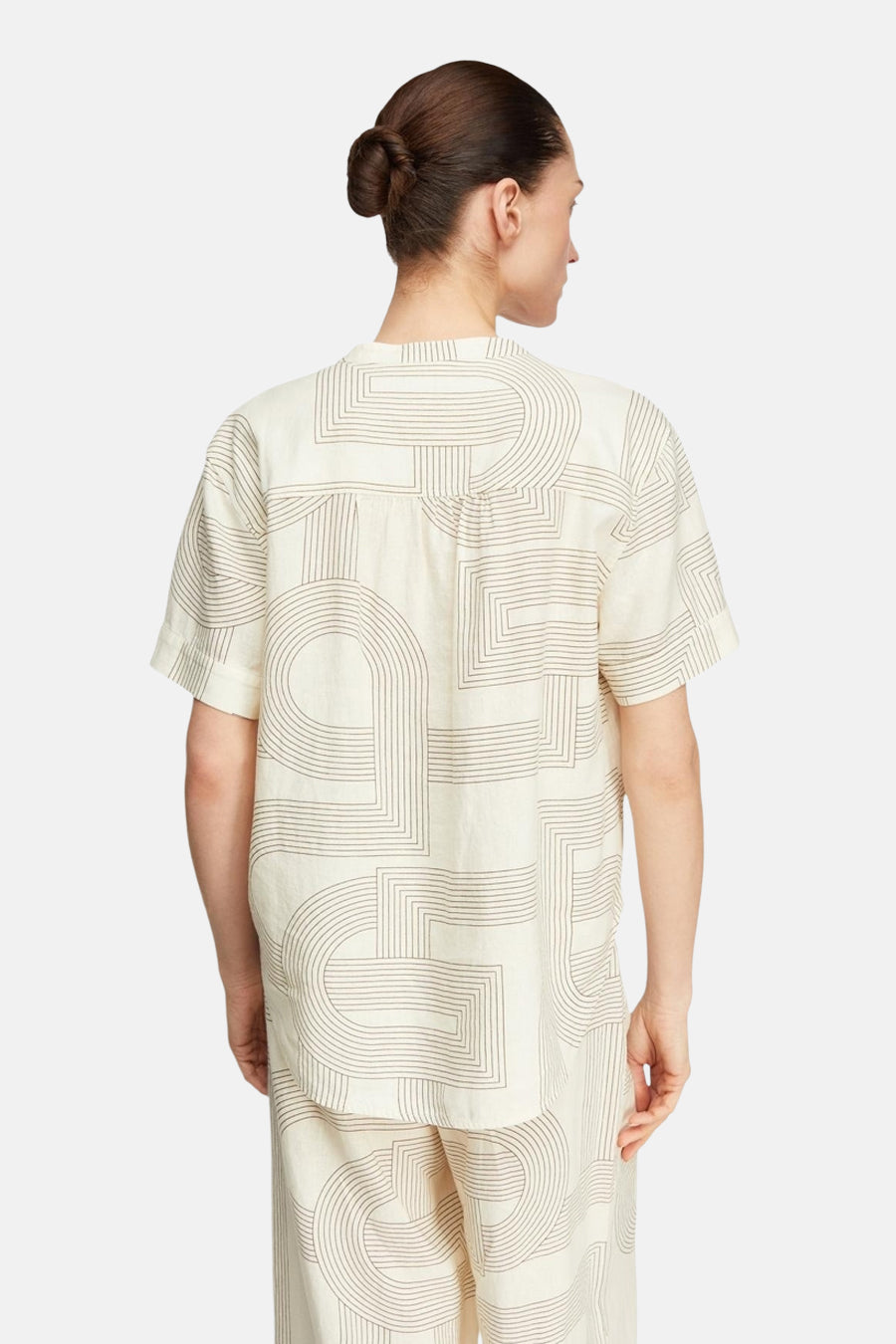 Blouse beige à manches courtes de COMMA avec motifs géométriques marron, vue de dos, portée avec un pantalon assorti.