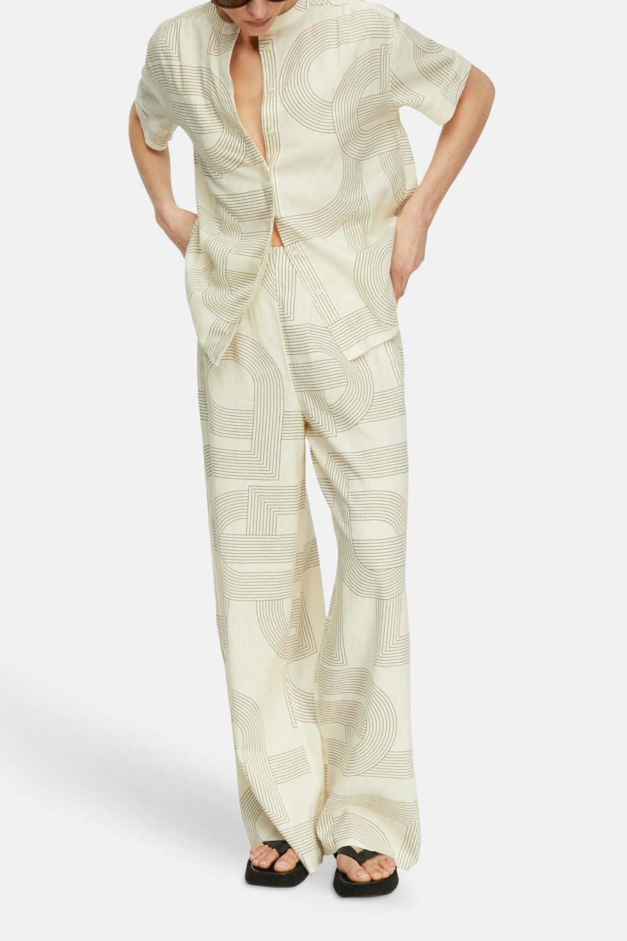 Blouse beige à manches courtes de COMMA avec motif géométrique linéaire marron, portée avec pantalon assorti.