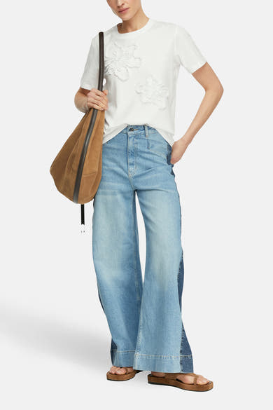 Wit T-shirt met decoratieve bloemen van COMMA, gedragen met een wijde jeans en bruine sandalen.