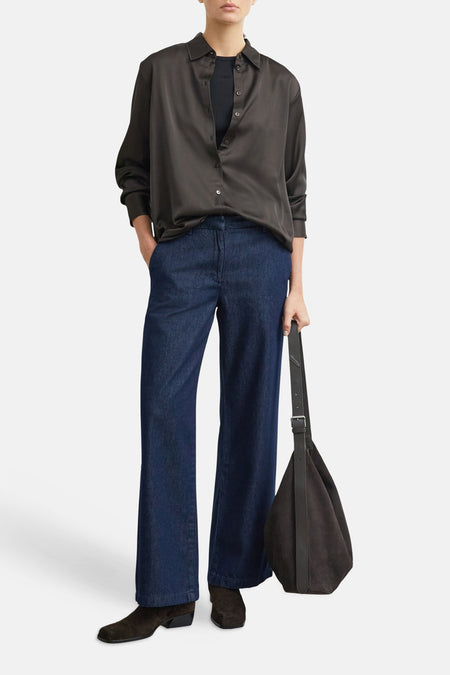 Jean large en denim bleu foncé de COMMA, coupe droite et fluide, porté avec chemise noire et sac en cuir, vue frontale.