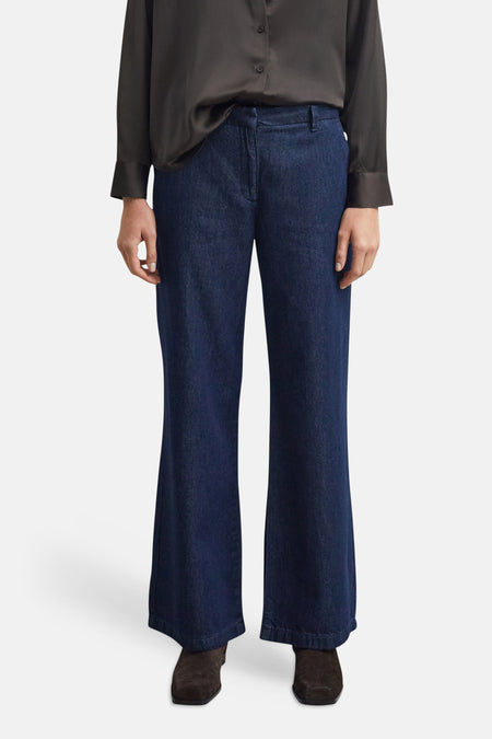 Jean large en denim bleu foncé par COMMA, coupe droite ample, porté avec chemise noire et bottines en daim, vue frontale.
