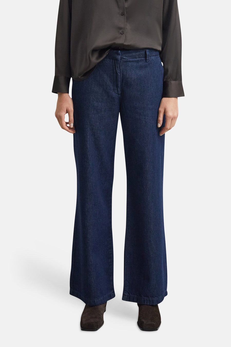 Jean large en denim bleu foncé par COMMA, coupe droite ample, porté avec chemise noire et bottines en daim, vue frontale.