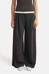 Brown wide-leg suit trousers by COMMA, featuring a smooth matte finish and front pleats, worn with a dark top and white shoes in a front view.