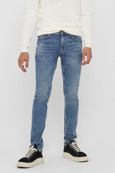 Jean slim bleu de ONLY & SONS, porté avec un pull blanc et des baskets noires à semelles compensées.