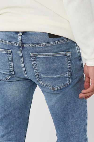 Blauwe slim fit jeans van ONLY & SONS, achterzakdetail, gedragen met een witte trui.