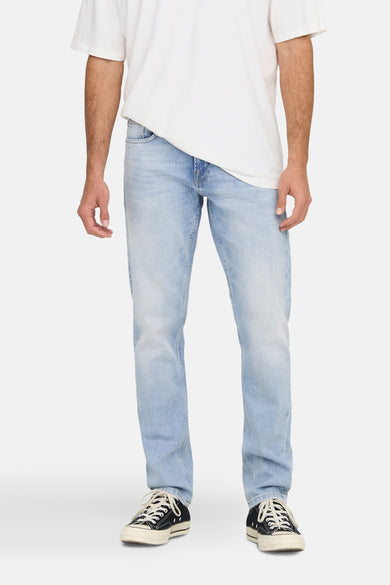 Jean droit bleu clair de ONLY & SONS, porté avec un t-shirt blanc et des baskets noires.