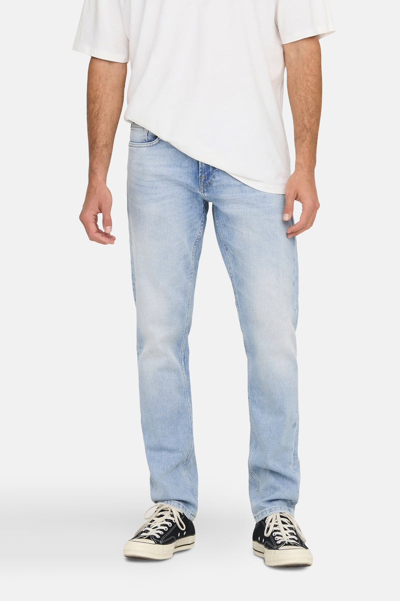 Jean droit bleu clair de ONLY & SONS, porté avec un t-shirt blanc et des baskets noires.