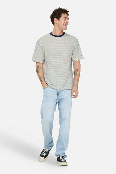 Light blue straight-leg denim jeans by WEFT, worn with striped tee and black sneakers, full-body front view