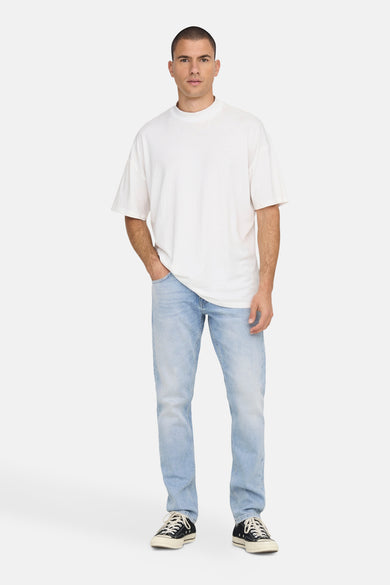 Jean droit bleu clair de ONLY & SONS®, porté avec un t-shirt blanc et des chaussures basses noires.