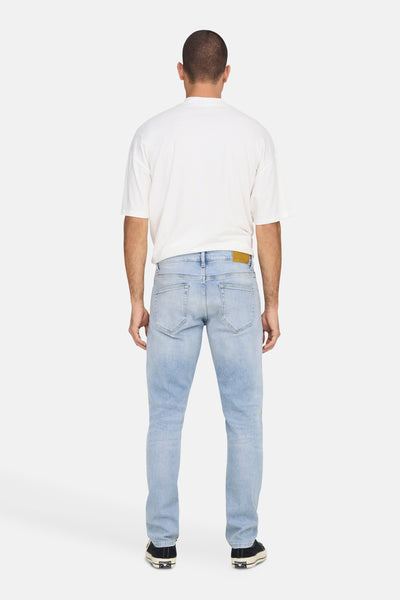Jean droit bleu clair de ONLY & SONS, avec poches arrière et chaussures de sport noires.
