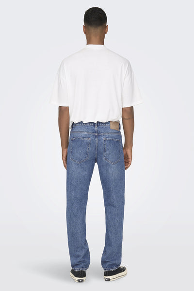 Jean large bleu de ONLY & SONS, coupe droite, porté avec un t-shirt blanc et des baskets noires.