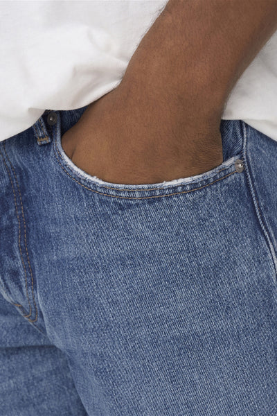 Wijde blauwe jeans van ONLY & SONS, met de hand in de zak, gedragen met een wit T-shirt.