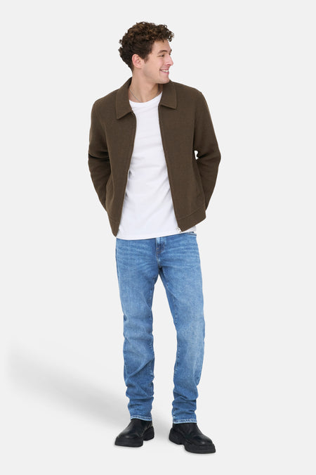 Jeans droit bleu moyen de Only & Sons, portés avec un t-shirt blanc et une veste marron.