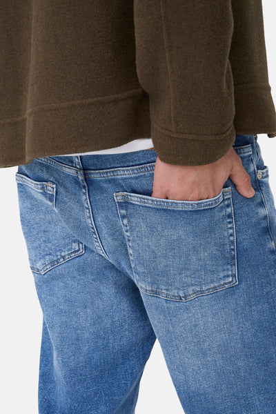 Jeans droits bleu moyen de ONLY & SONS®, avec une main dans la poche arrière et ourlet brut.
