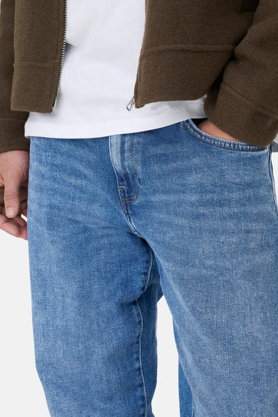 Jean droit bleu moyen de ONLY & SONS, porté avec un t-shirt blanc et une veste marron.