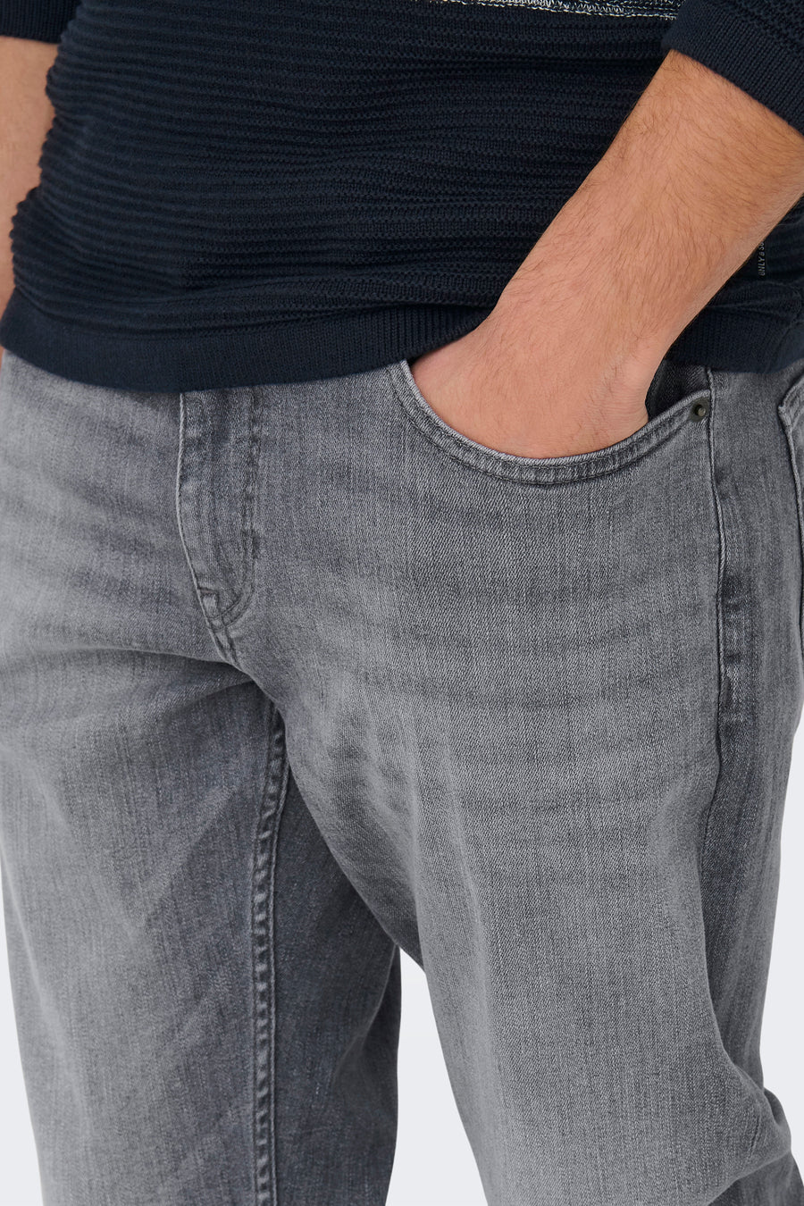 Lichtgrijze rechte jeans van ONLY & SONS®, met een hand in de zak, gedragen met een marineblauwe trui.