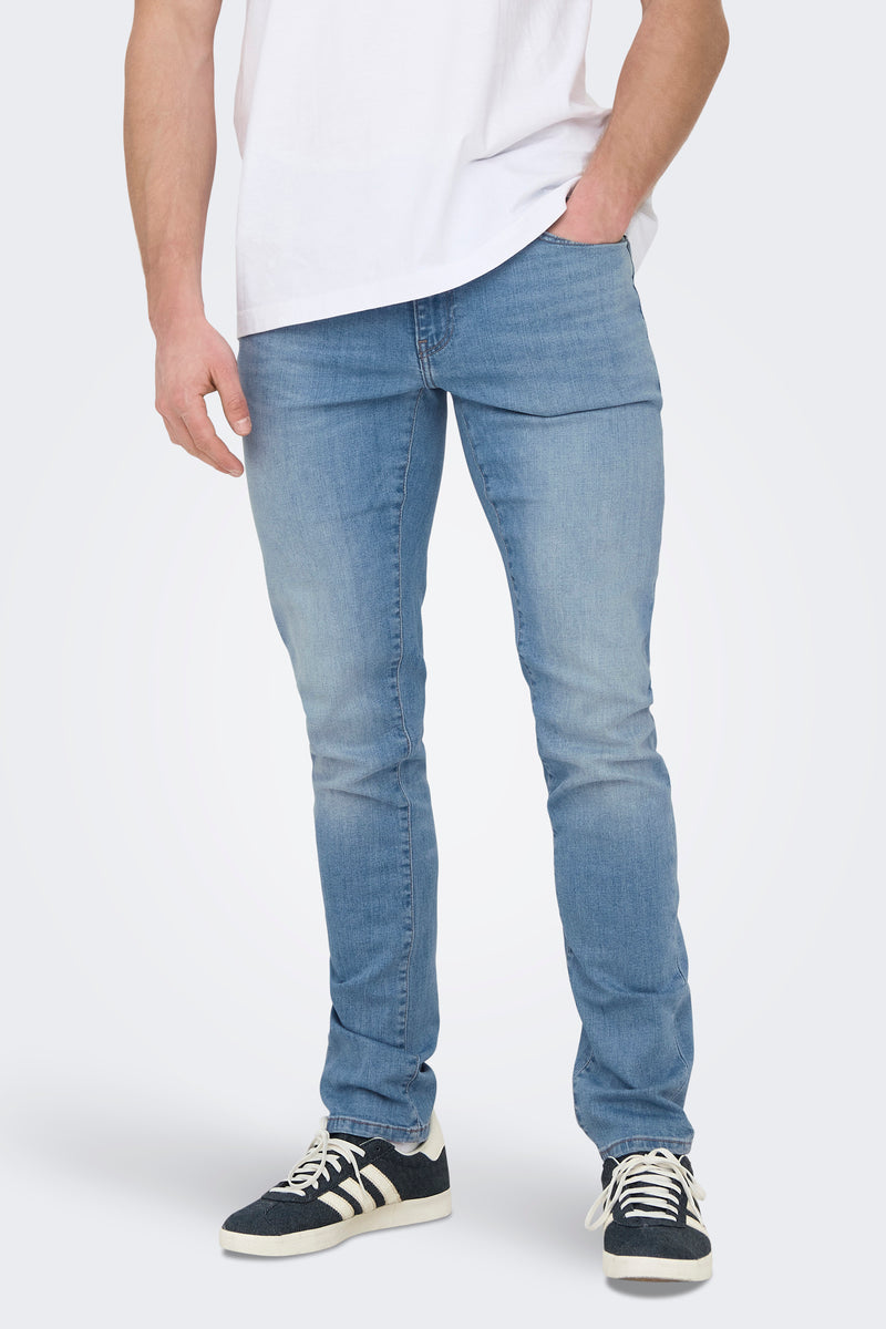 Jeans slim en denim bleu clair de ONLY & SONS, portés avec un t-shirt blanc et des baskets sombres.
