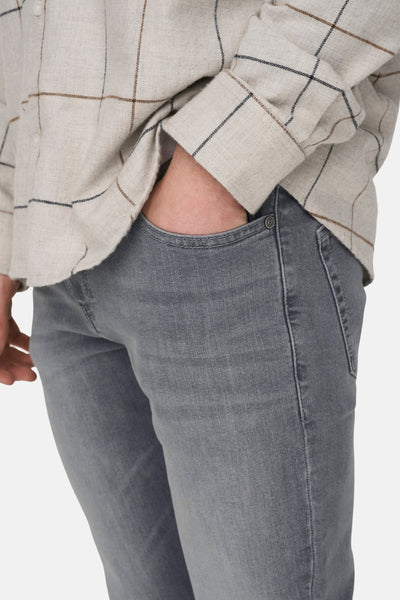 Lichtgrijze denim slim fit jeans van ONLY & SONS, met een hand in de zak en een beige geruit overhemd.