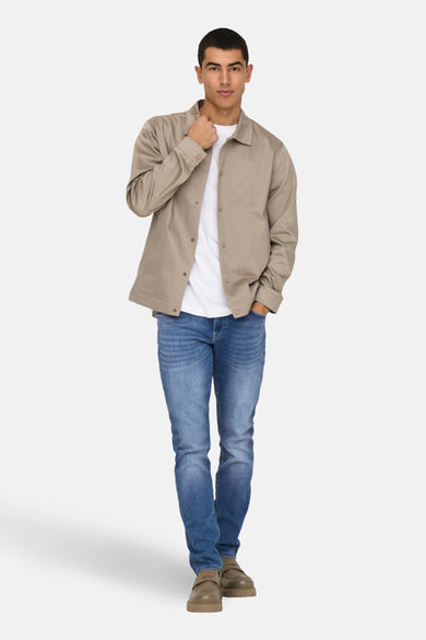 Middelblauwe slim fit jeans van ONLY & SONS, gedragen met een beige jasje en een wit T-shirt.