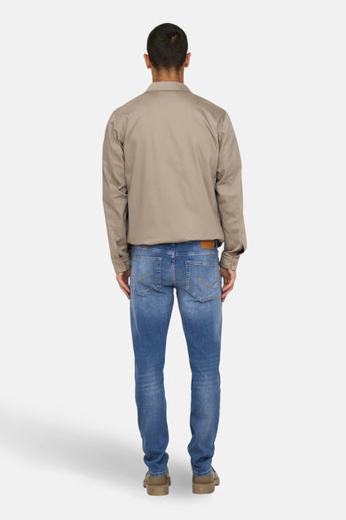 Slim jeans in medium blue denim van ONLY & SONS, met decoratieve achterzakken, gedragen met een beige jas.