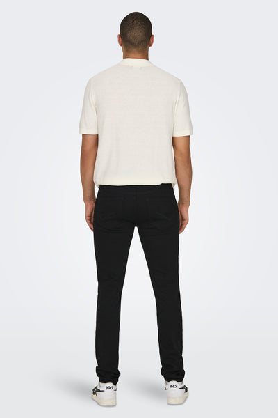 Jean slim noir en denim de ONLY & SONS®, vue de dos, porté avec un polo écru et des baskets blanches.
