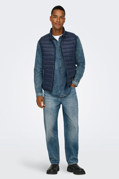 Rechte spijkerbroek in middinblauw denim van ONLY & SONS, gedragen met een spijkeroverhemd en een gewatteerd vest.
