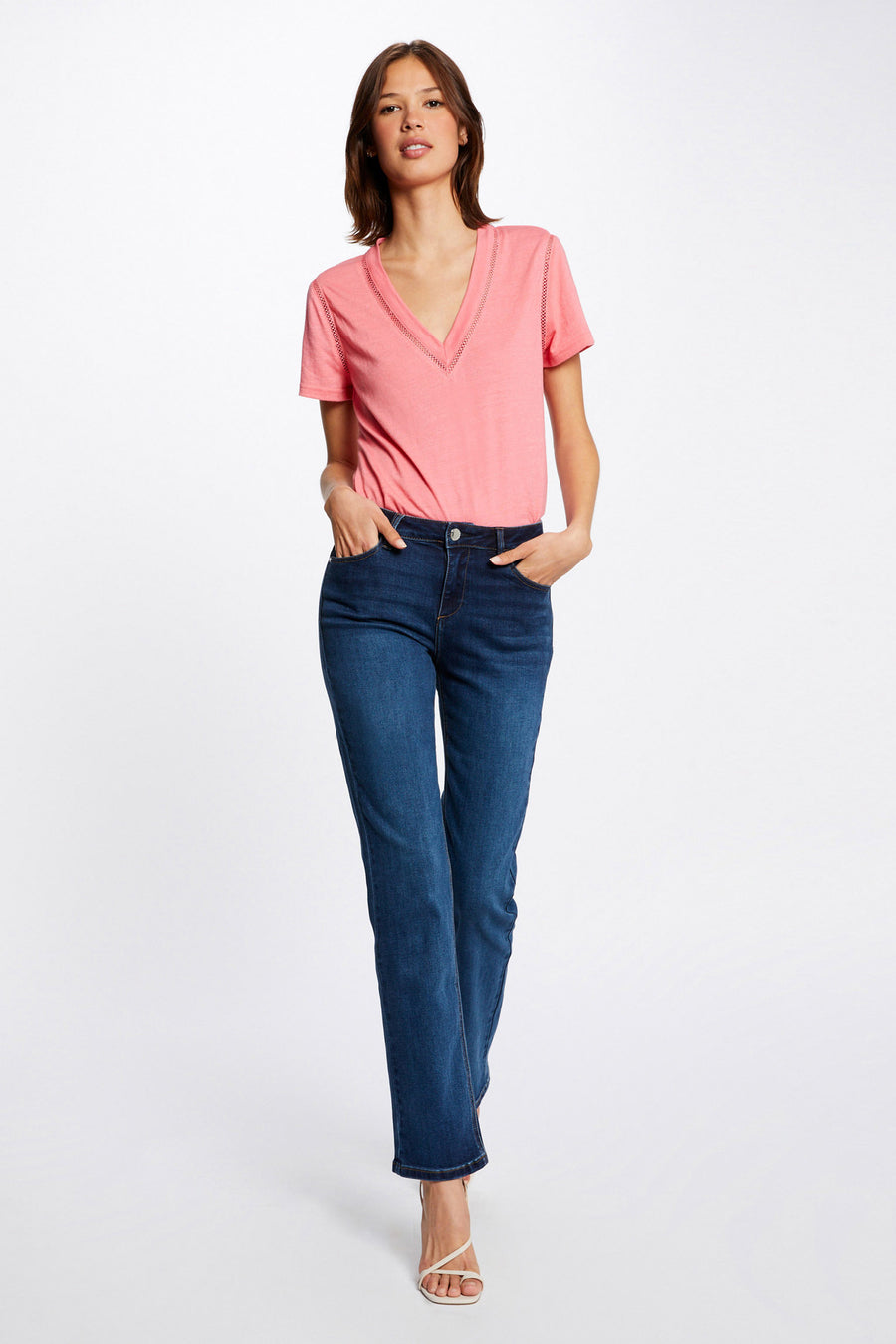 Jean droit bleu de Morgan de Toi, porté avec un t-shirt rose et des sandales blanches à talons.