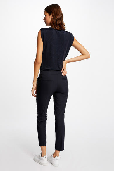 Pantalon de costume noir par Morgan de Toi, coupe fuselée, porté avec des chaussures de sport blanches.