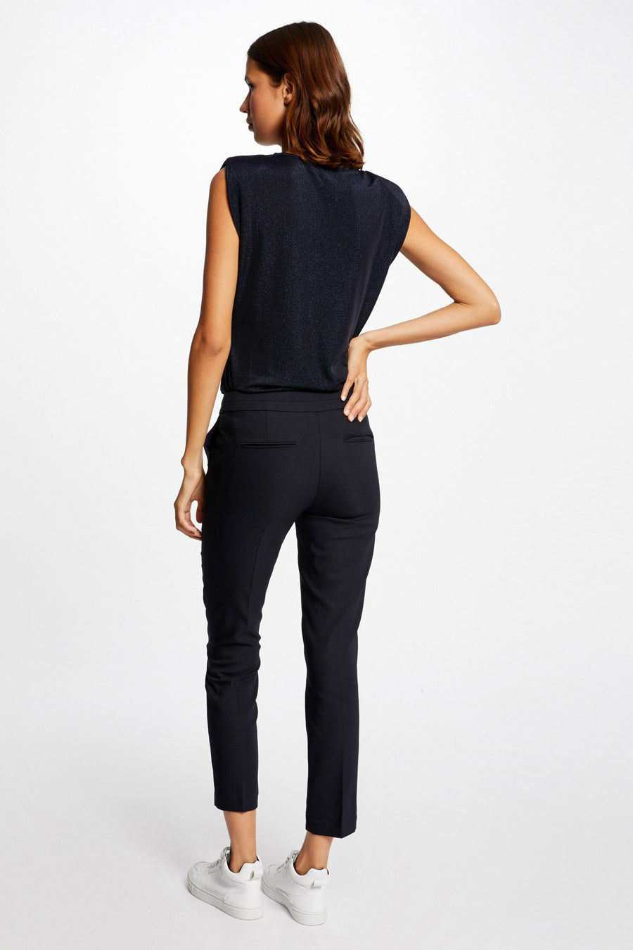 Pantalon de costume noir par Morgan de Toi, coupe fuselée, porté avec des chaussures de sport blanches.