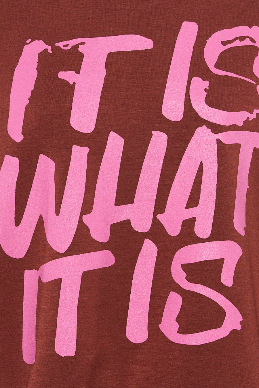 Multicolored crewneck sweatshirt with bold pink graffiti-style text "IT IS WHAT IT IS" on deep red fabric, close-up front view