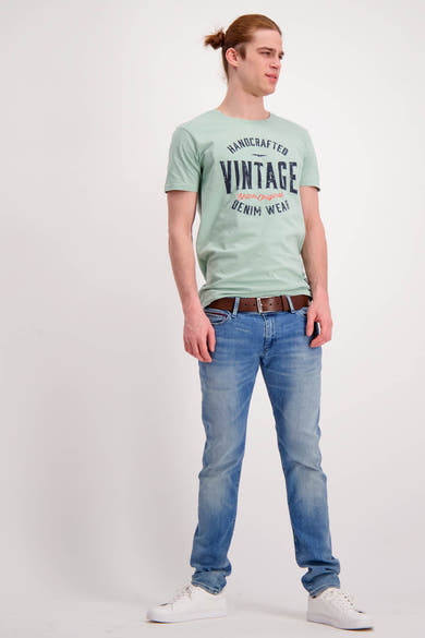 Ceinture marron de Levi's Accessories, avec boucle argentée, portée avec un jean bleu et des baskets blanches.
