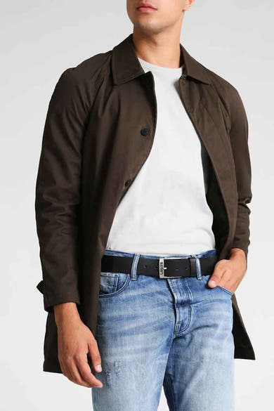 Ceinture noire de Levi's, portée avec un jean bleu et un manteau marron.