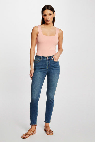 Jean slim en denim bleu foncé de Morgan de Toi, porté avec un haut rose et des sandales marron.
