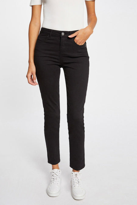 Pantalon coloré noir de Morgan de Toi, porté avec un t-shirt blanc et des baskets blanches montantes.
