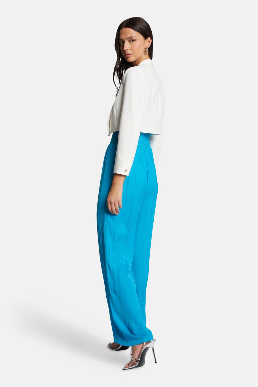 Veste écru de Morgan de Toi, courte avec des boutons dorés, portée avec un pantalon bleu turquoise ample et des talons hauts argentés.
