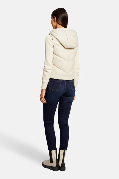Veste sans manches écru de Morgan de Toi, matelassée avec capuche, portée sur un jean bleu et des bottines bicolores.