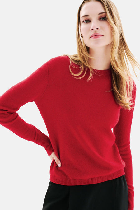 Pull rouge à col rond de CAROLL, porté avec un pantalon noir, sur fond blanc.