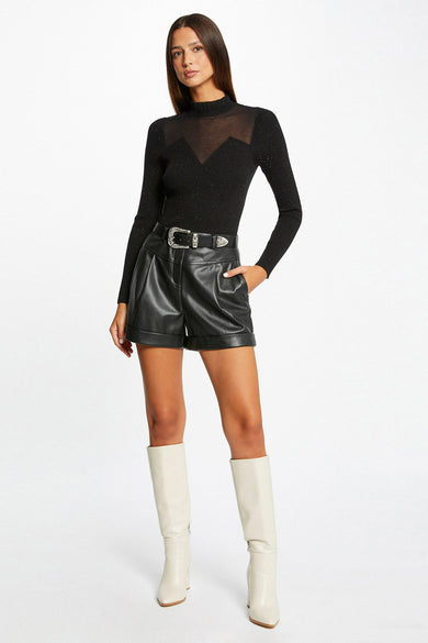 Black ribbed turtleneck pullover with sheer mesh yoke, paired with faux leather shorts and white boots, full-length front view